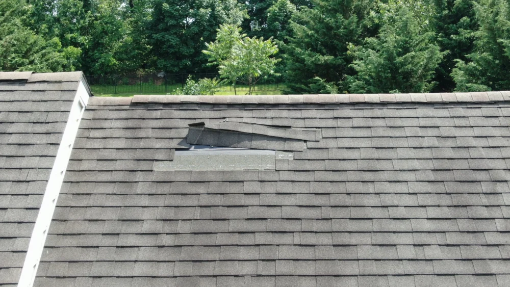 Minor roofing storm damage showing small cracks and missing granules on asphalt shingles after a storm